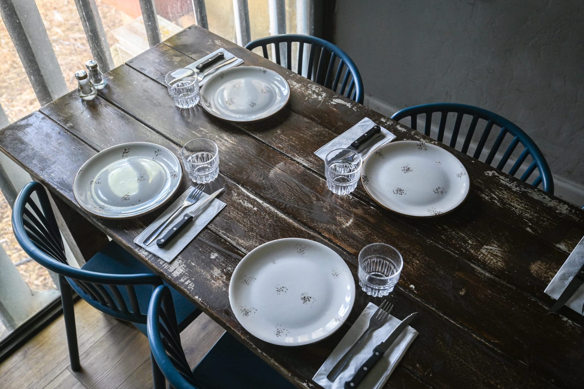 שולחן עץ ערוך עם כיסאות כחולים ליד החלון
